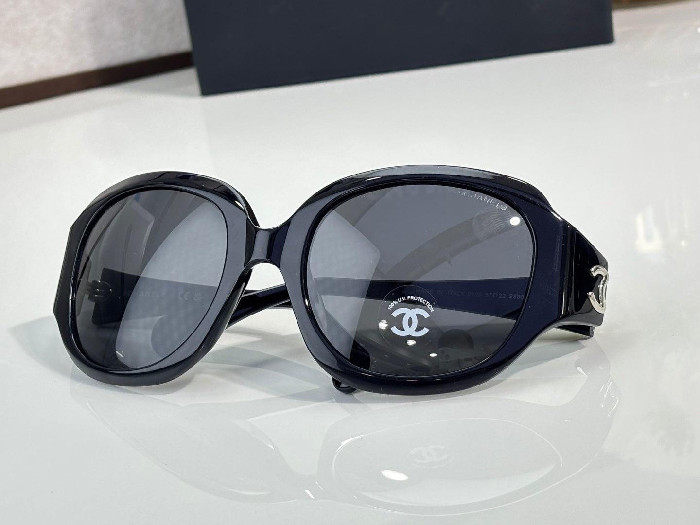 Black round sunglasses with wide frames and CHANEL logo on lens