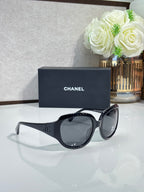 Black sunglasses with CHANEL temple logo and dark lenses, side view