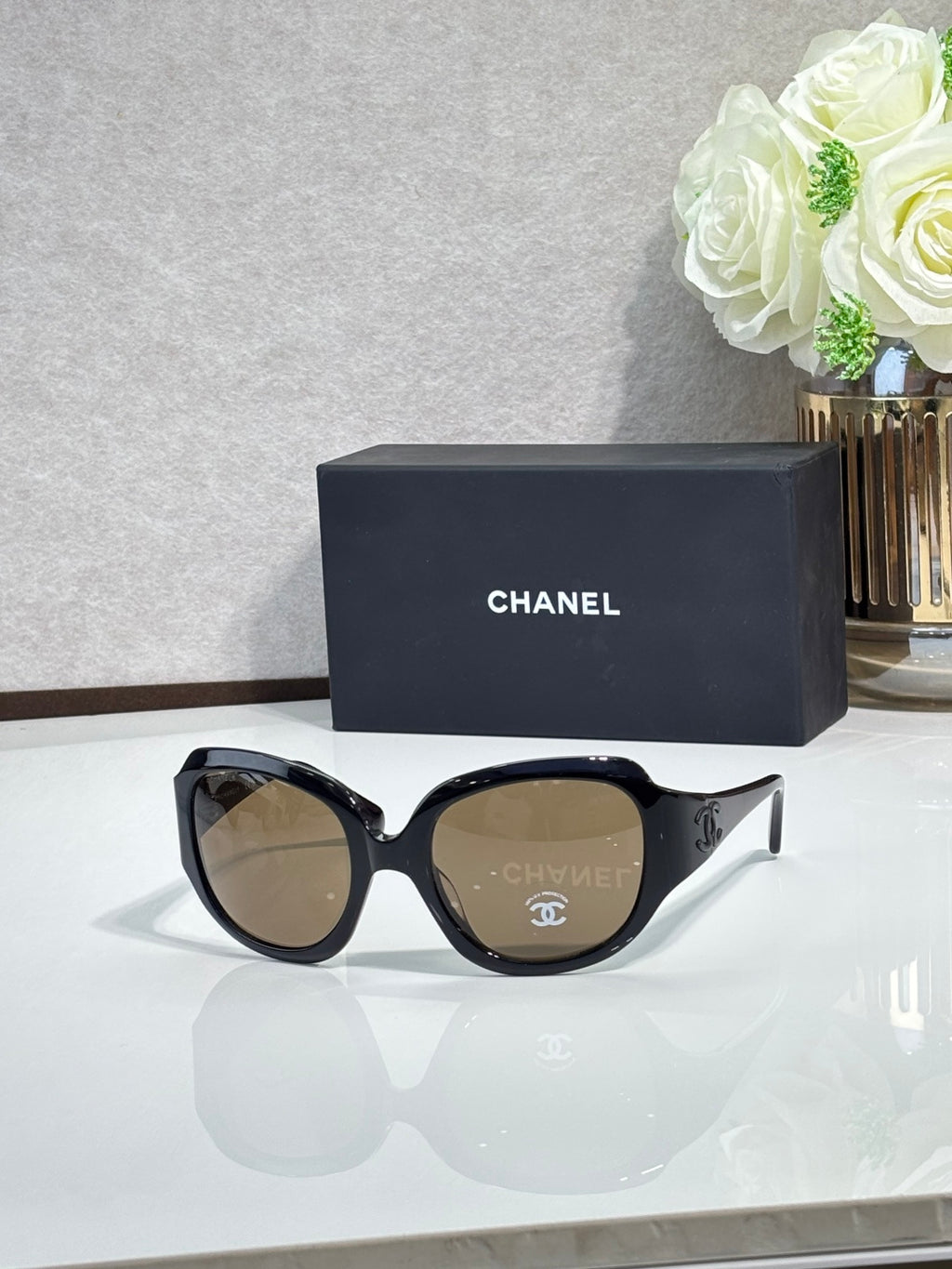 Black sunglasses with CHANEL temple detail and brown-tinted lenses