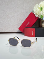 Prada sunglasses with gold-tone frame and dark gray tinted lenses, oval shape