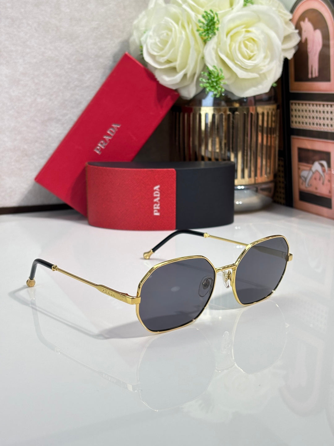 Prada sunglasses with gold-tone frame and dark tinted lenses, angled oval design