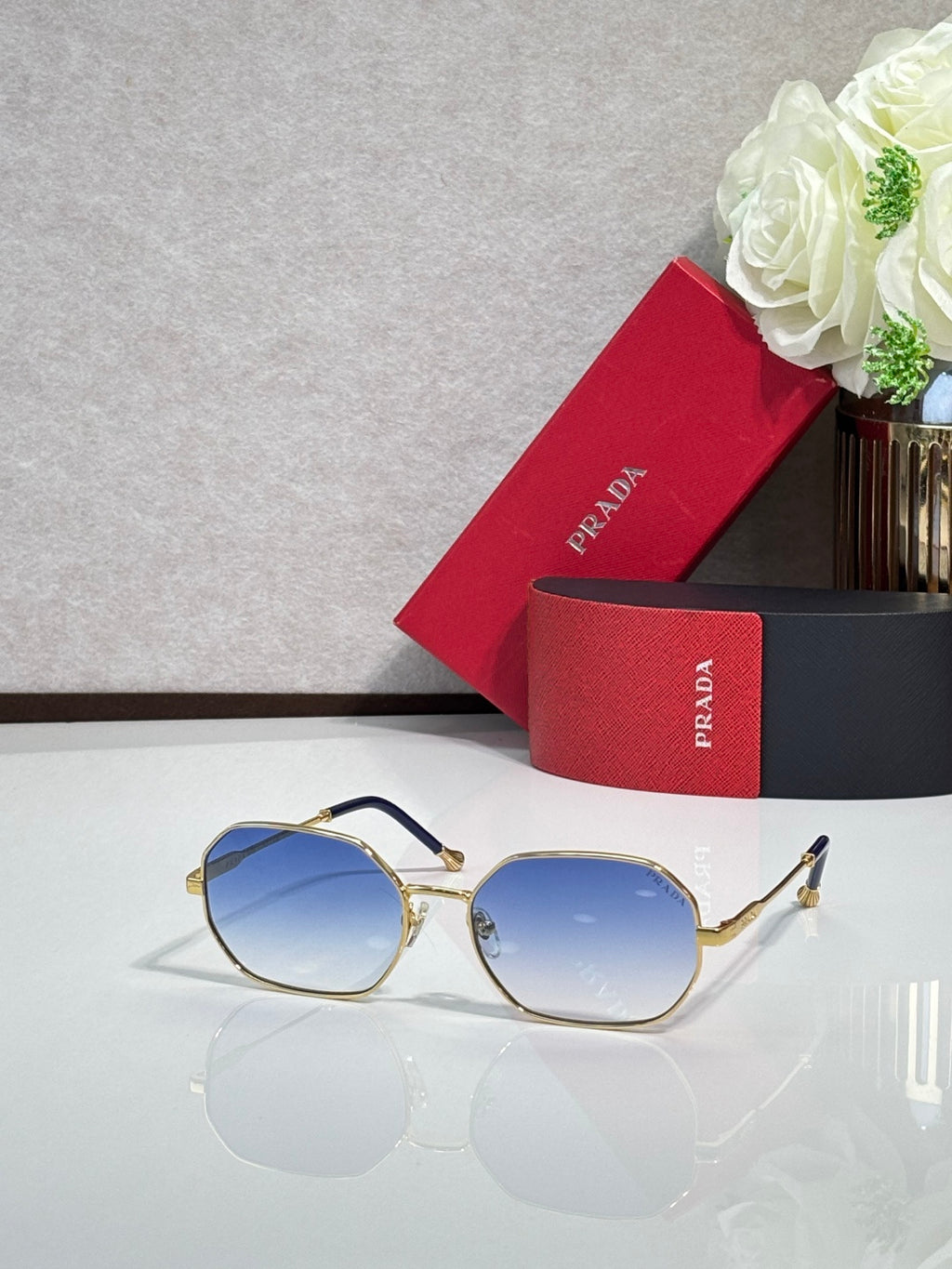 Prada sunglasses with gold-tone frame and blue tinted lenses, rounded square-oval