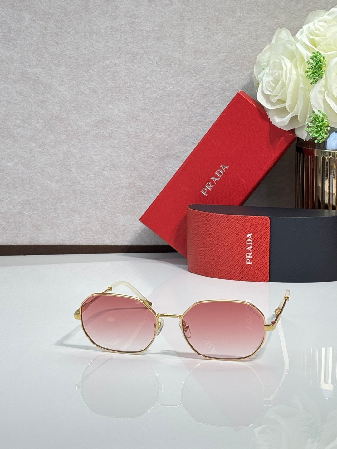 Prada sunglasses with gold-tone frame and pink tinted lenses, rounded oval shape