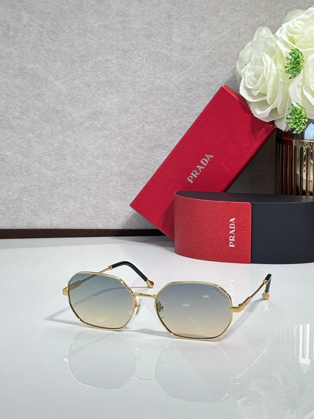 Prada sunglasses with gold-tone frame and light blue tinted lenses, oval shape