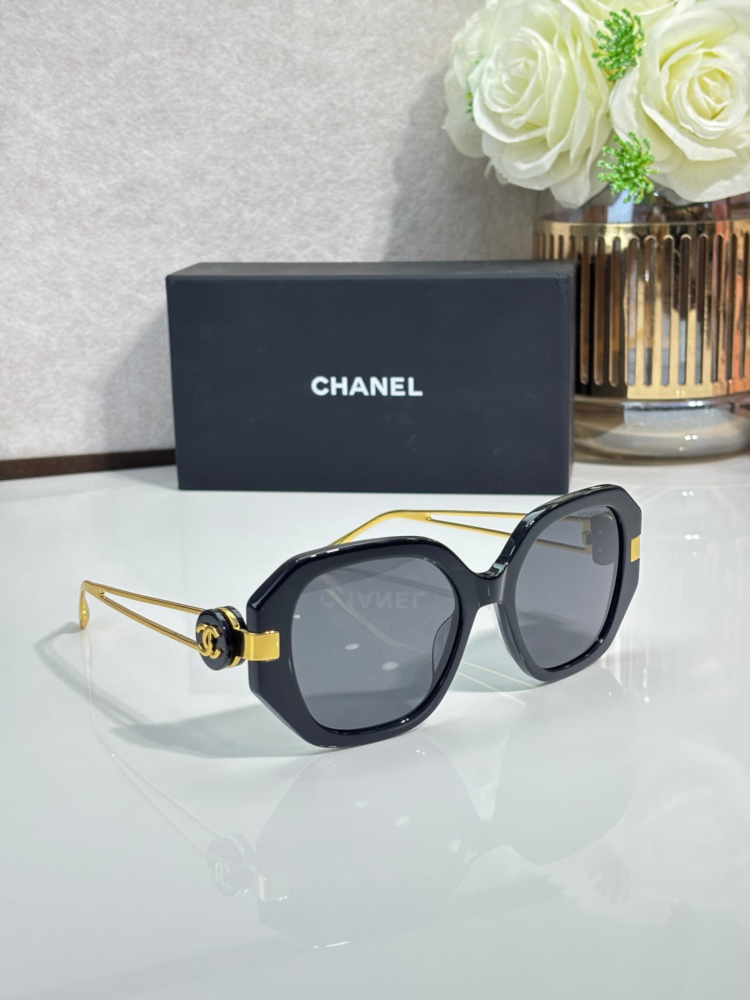 Chanel cat-eye sunglasses with dark frames, tinted lenses, and gold-tone hinge details