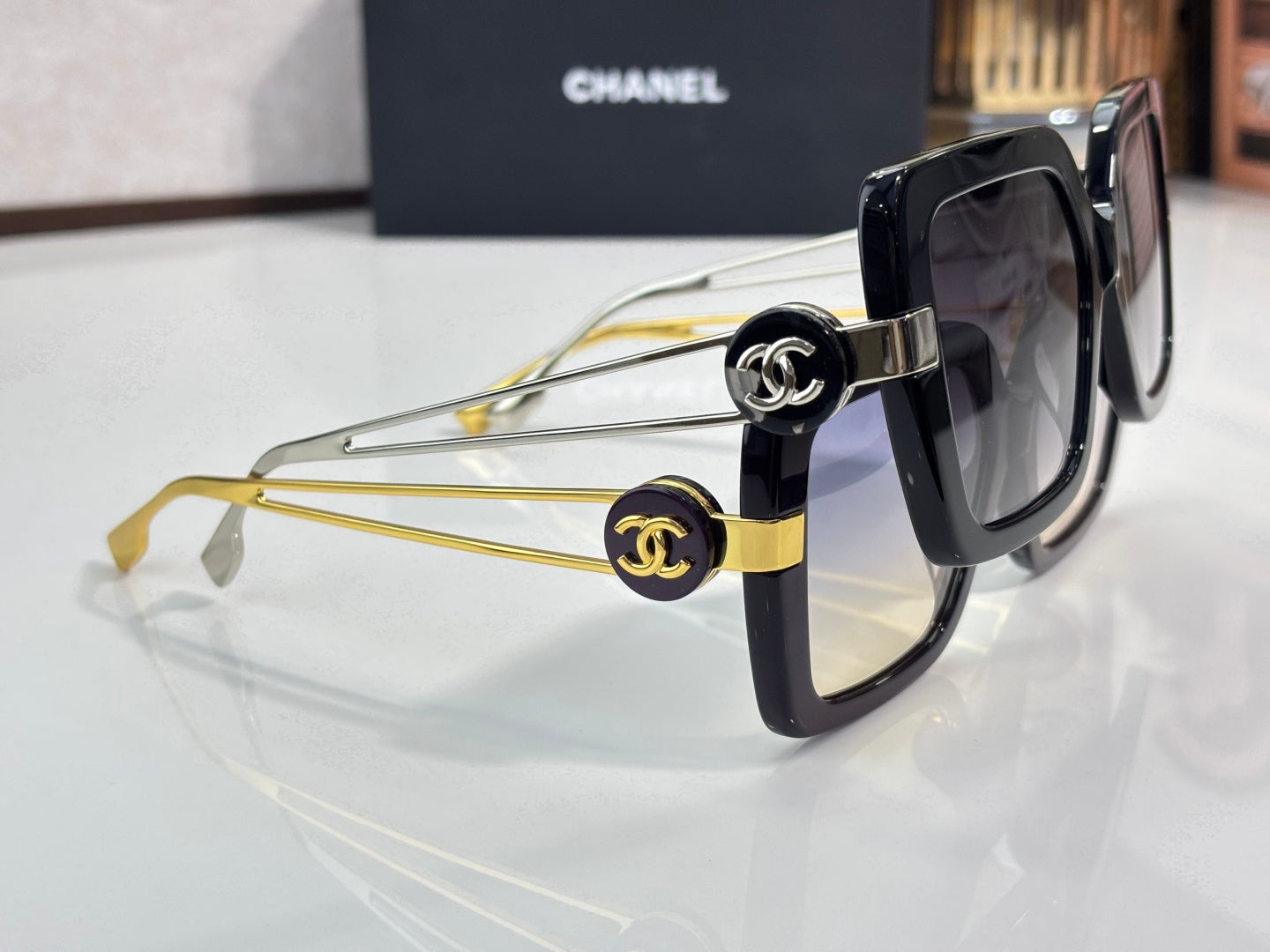 Chanel square sunglasses close-up with black frames and gold logo hardware