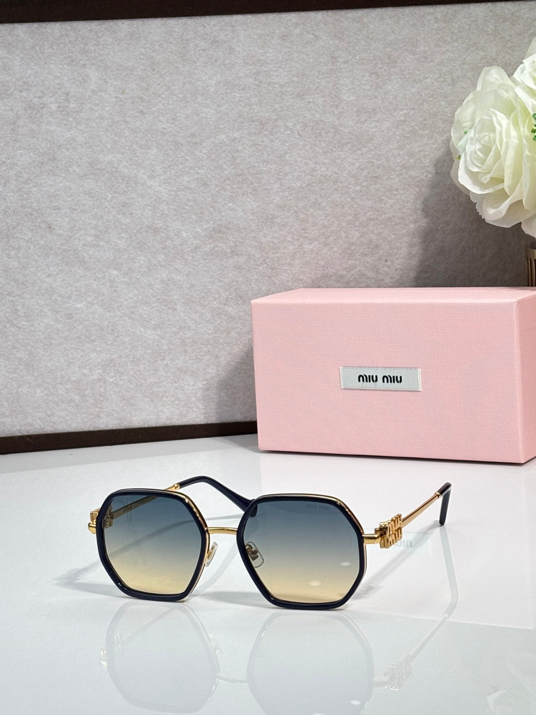 Square sunglasses with dark frame and tinted lenses, gold-toned temple detail