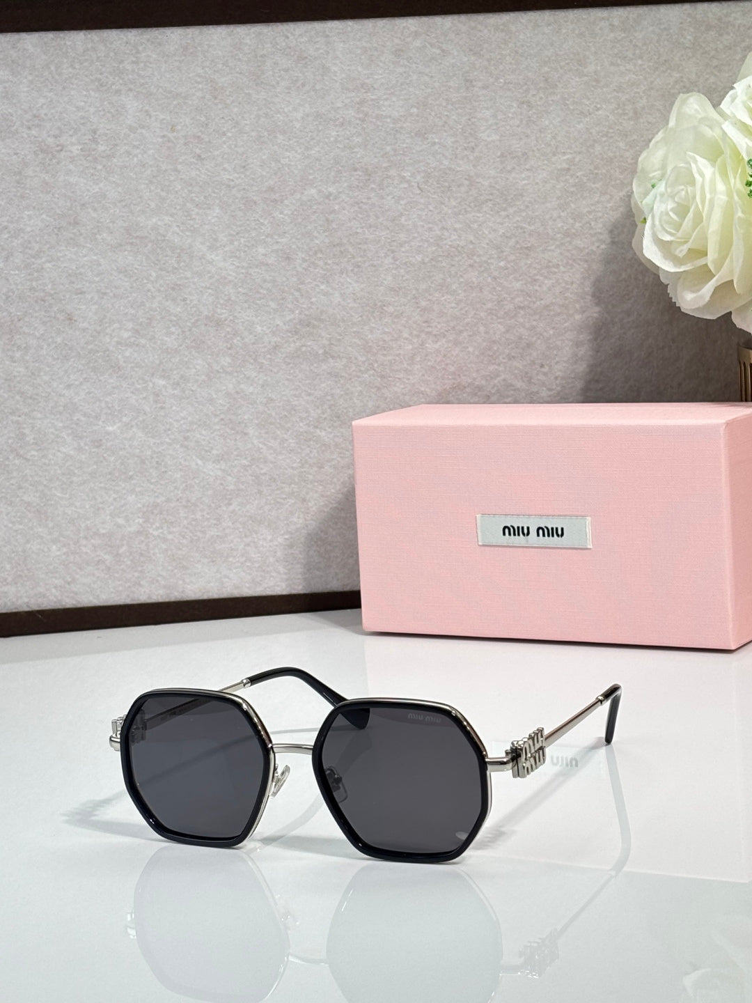 Square sunglasses with black frame and dark lenses, metallic detail on temples