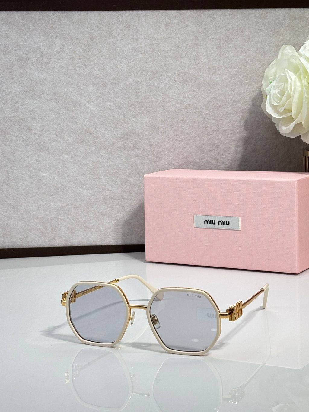 Square sunglasses with light-colored frame and pale blue tinted lenses, gold-toned temples