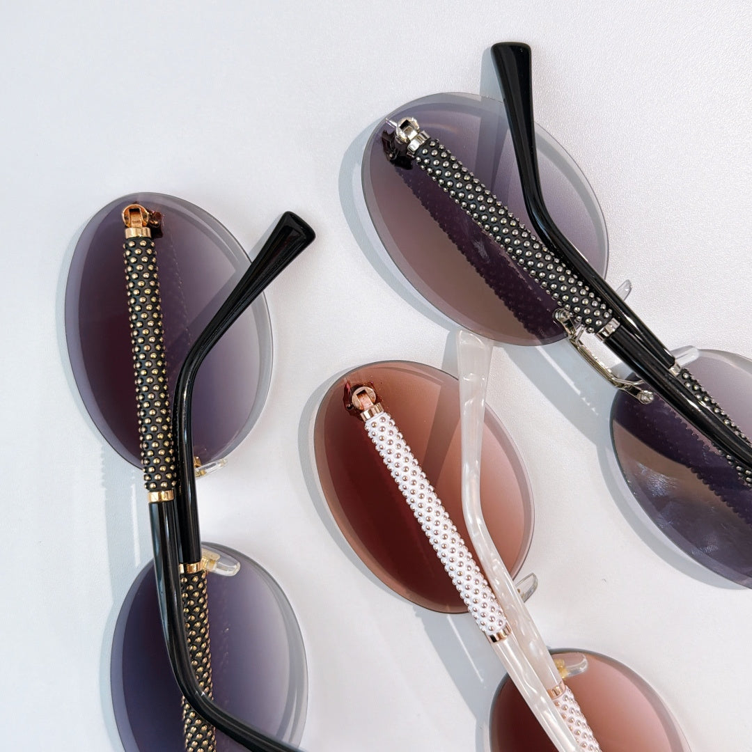 Set of sunglasses with purple, white, and dark frames and textured arms