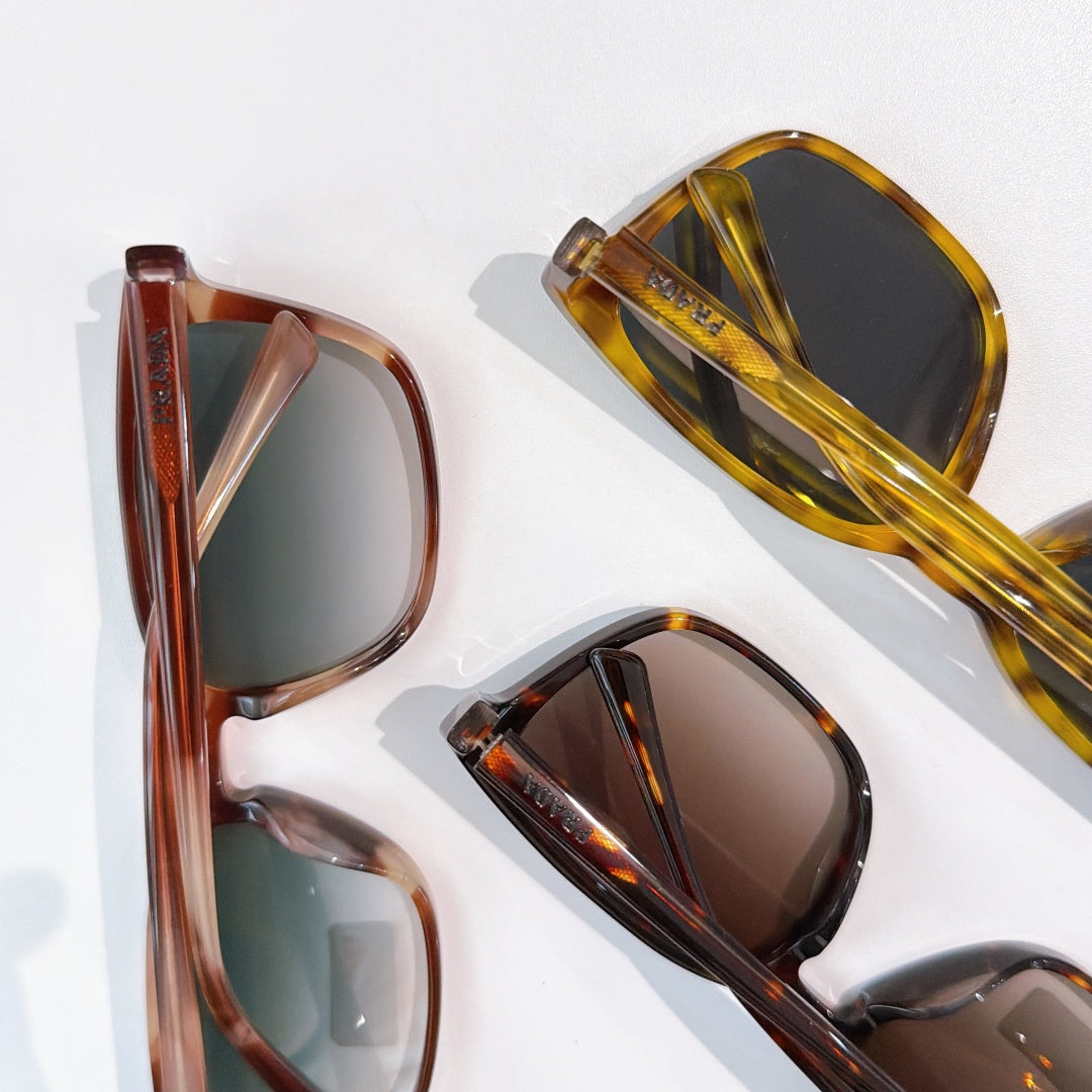 Three Prada sunglasses with mixed frame colors and tinted lenses