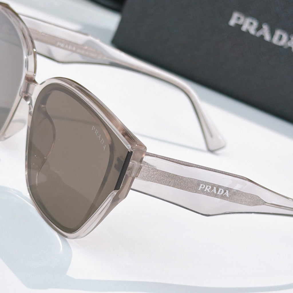 Prada sunglasses close-up with clear frames, brown lenses, and Prada logo temple