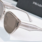 Prada sunglasses close-up with clear frames, brown lenses, and Prada logo temple