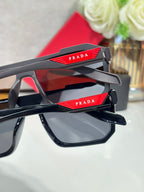 Prada sunglasses temple close-up with red logo detail and dark frame