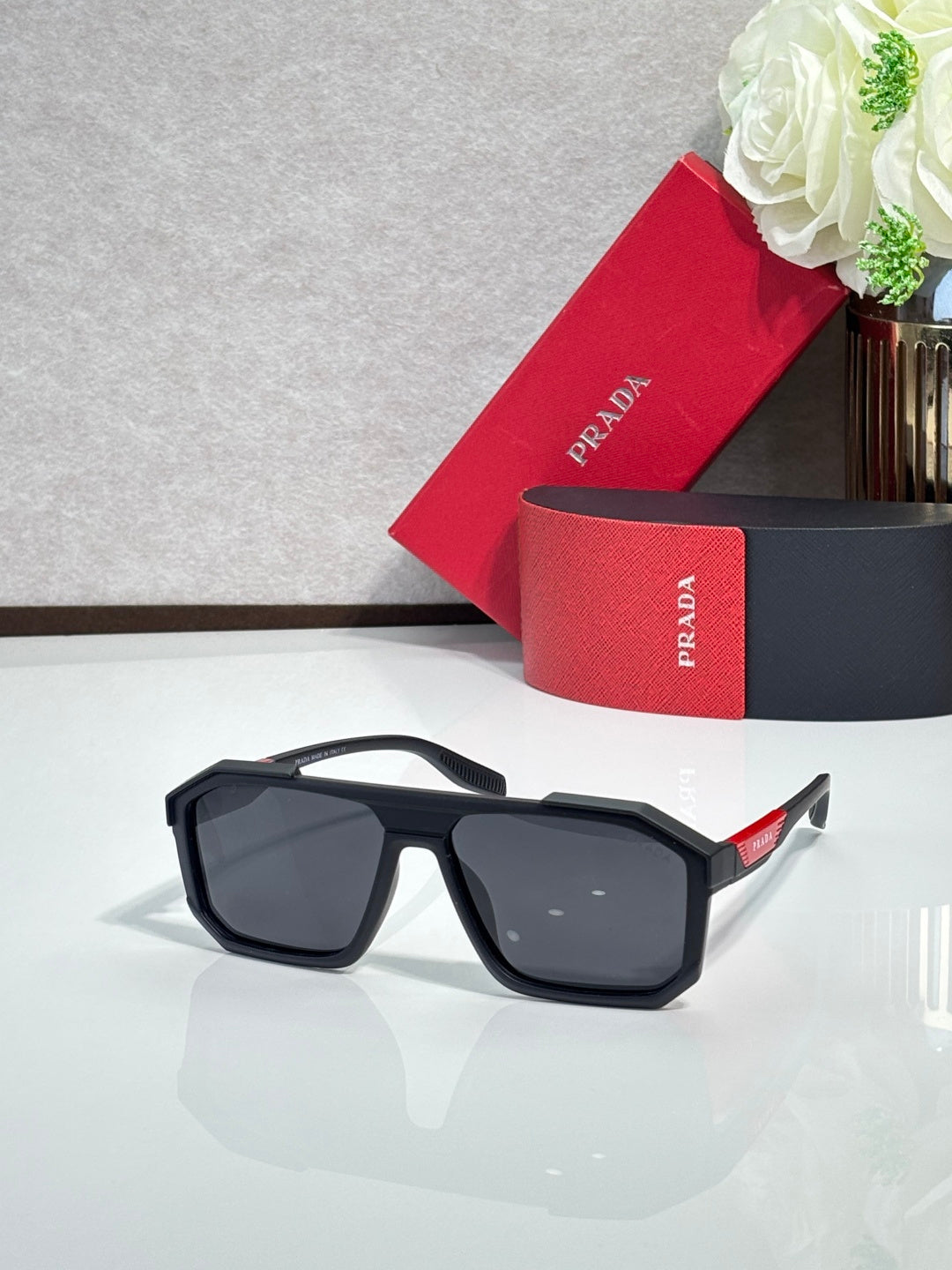 Rectangular black sunglasses with dark lenses and side logo detail on temples