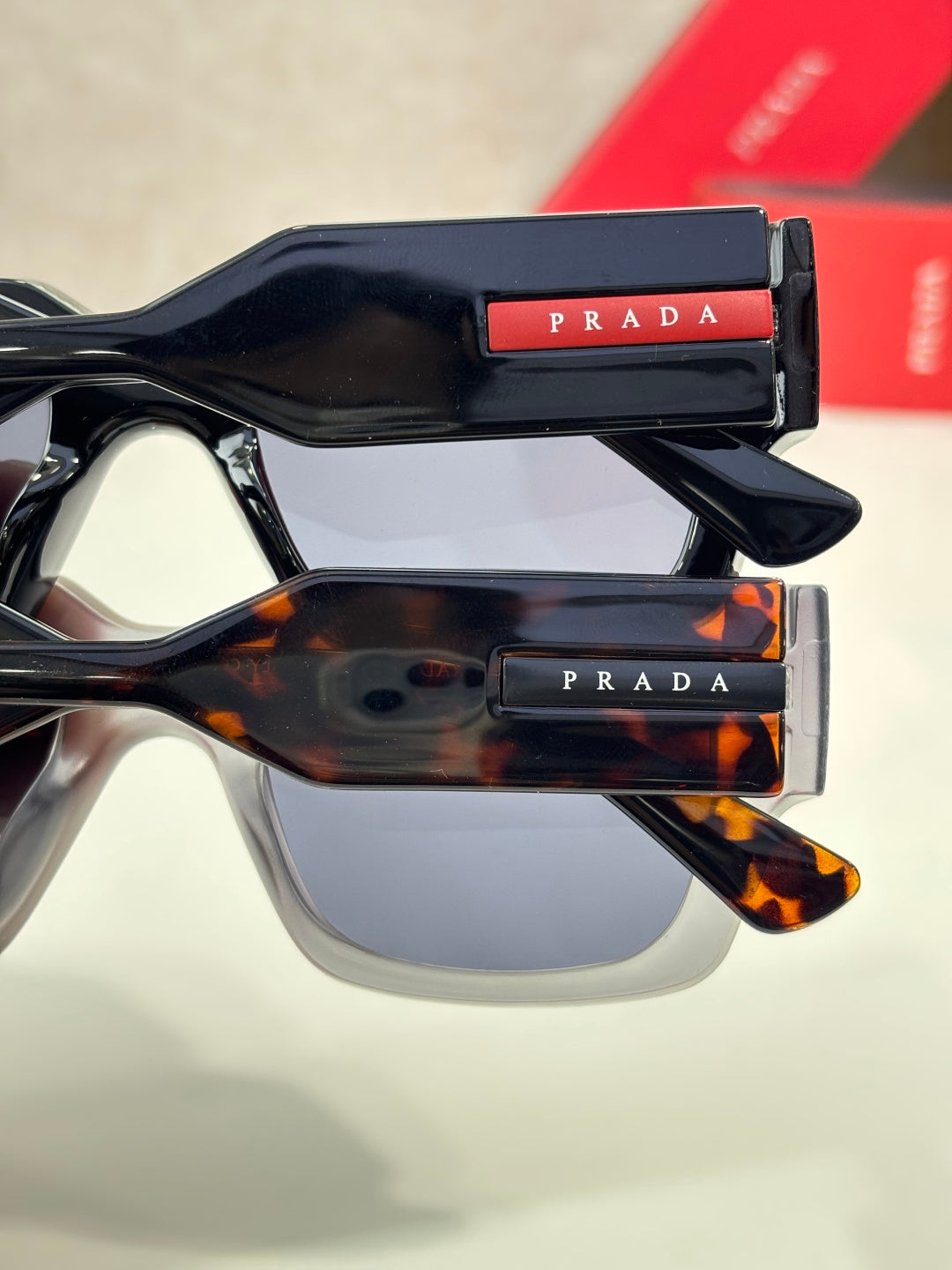 Stacked sunglasses: black and tortoiseshell frames with dark lenses and Prada logos