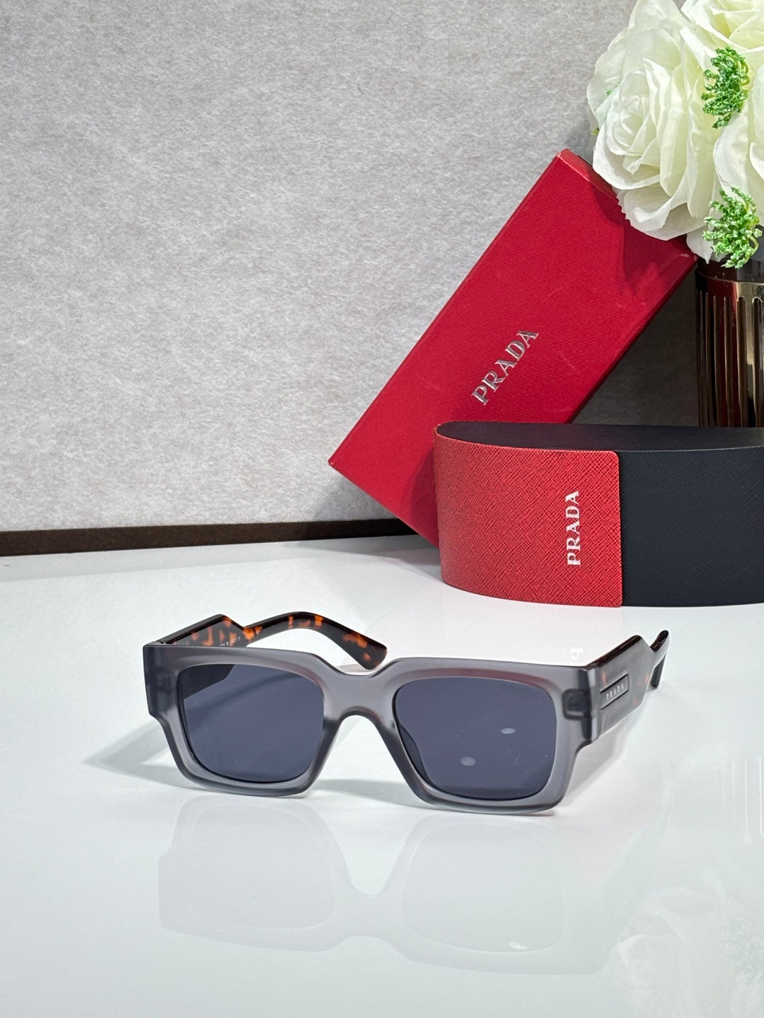 Gray oversized sunglasses with dark lenses and angular frame arms
