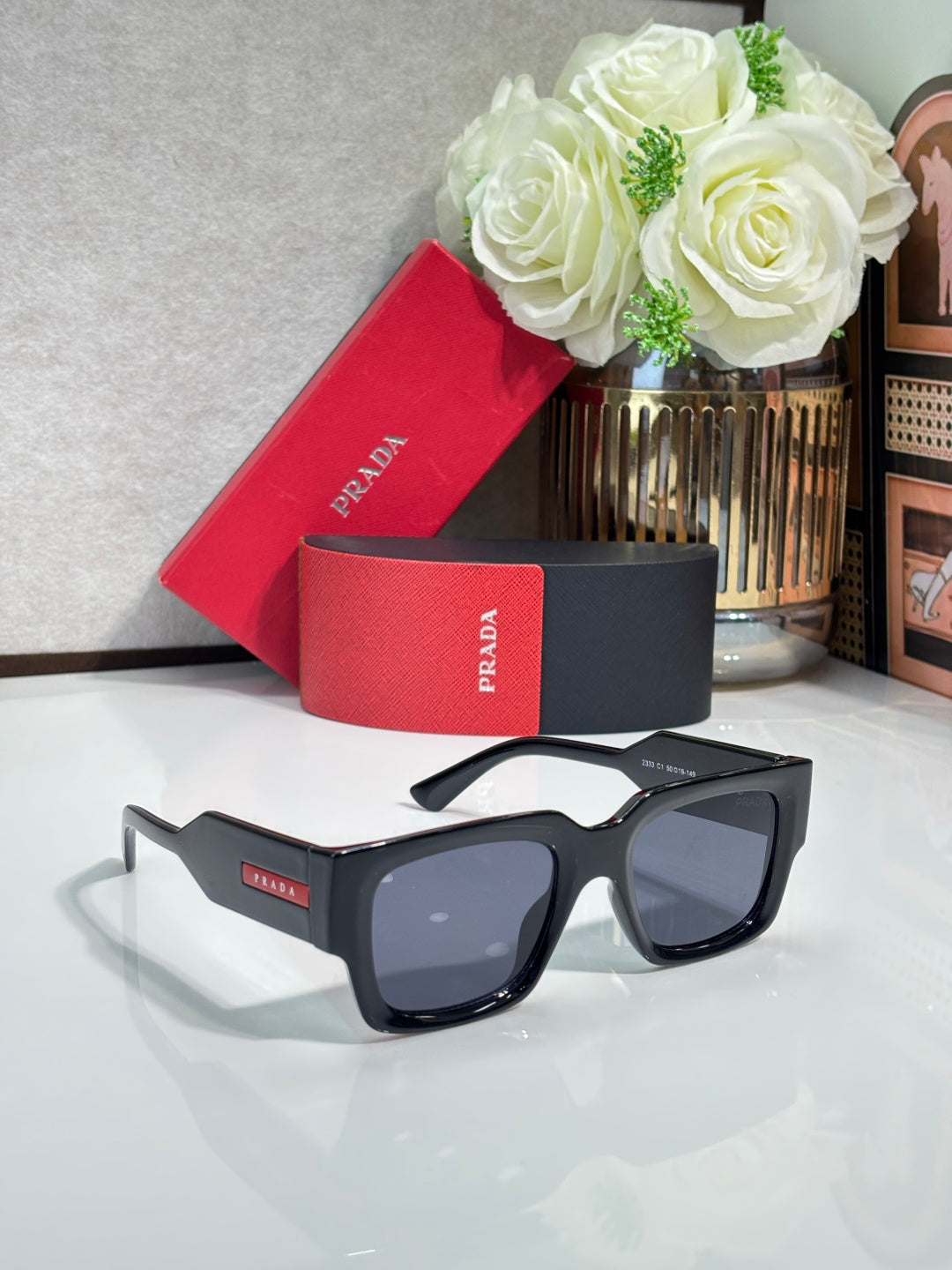 Black oversized sunglasses with dark lenses and Prada logo on the temple