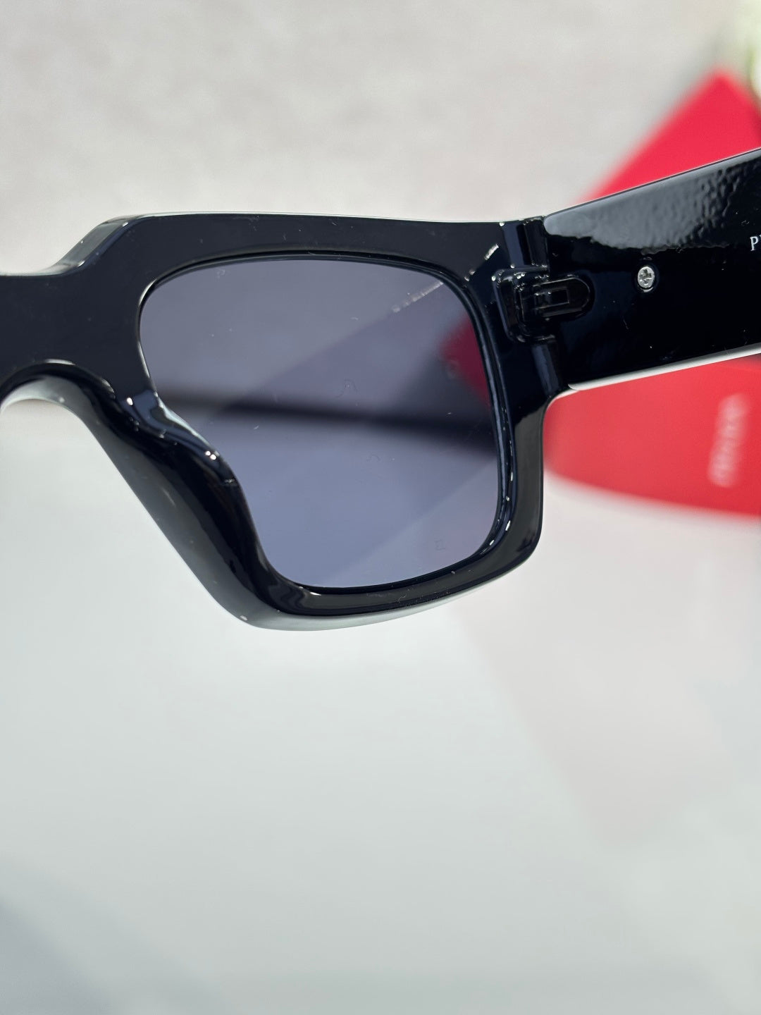 Black square sunglasses close-up with dark lenses and glossy frame edge