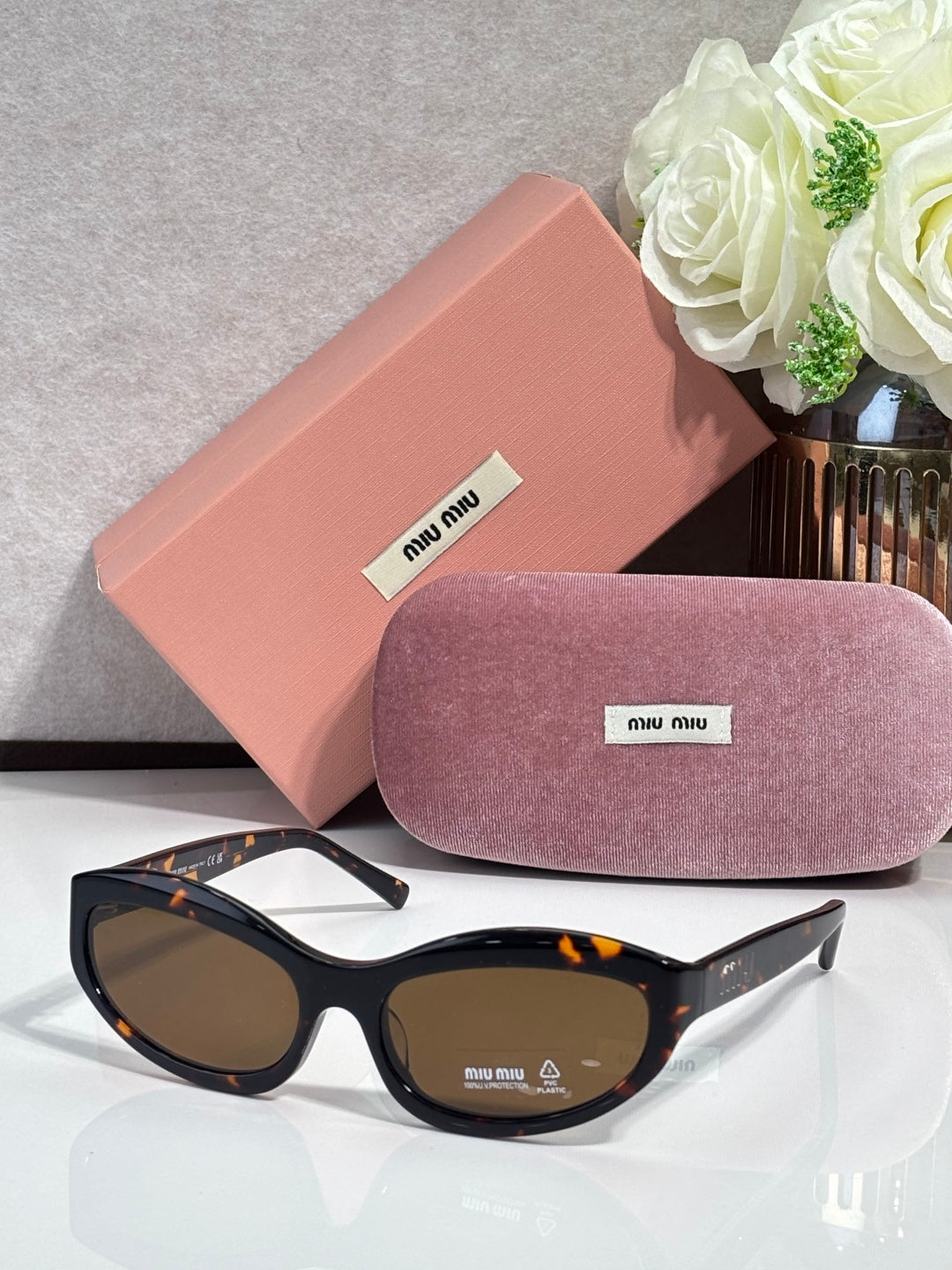 Black sunglasses with dark lenses; pink hard case and purple glasses pouch