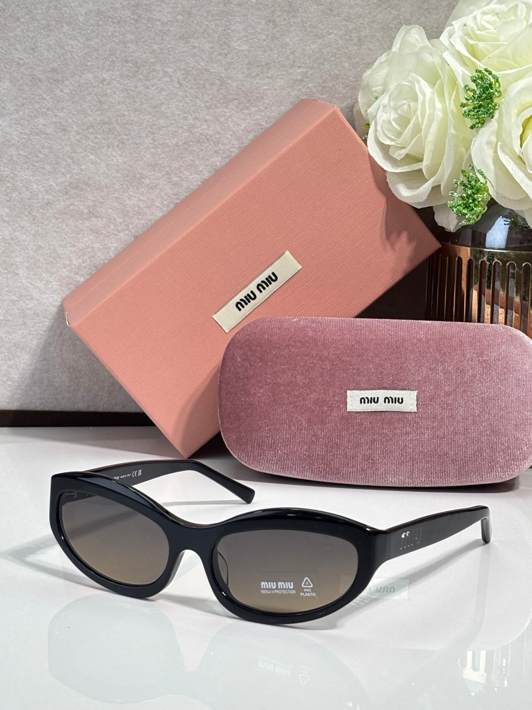 Black sunglasses with dark lenses; pink hard case and purple glasses pouch