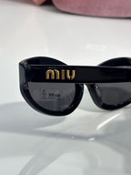 Black sunglasses with dark lenses and gold logo detail on the frame