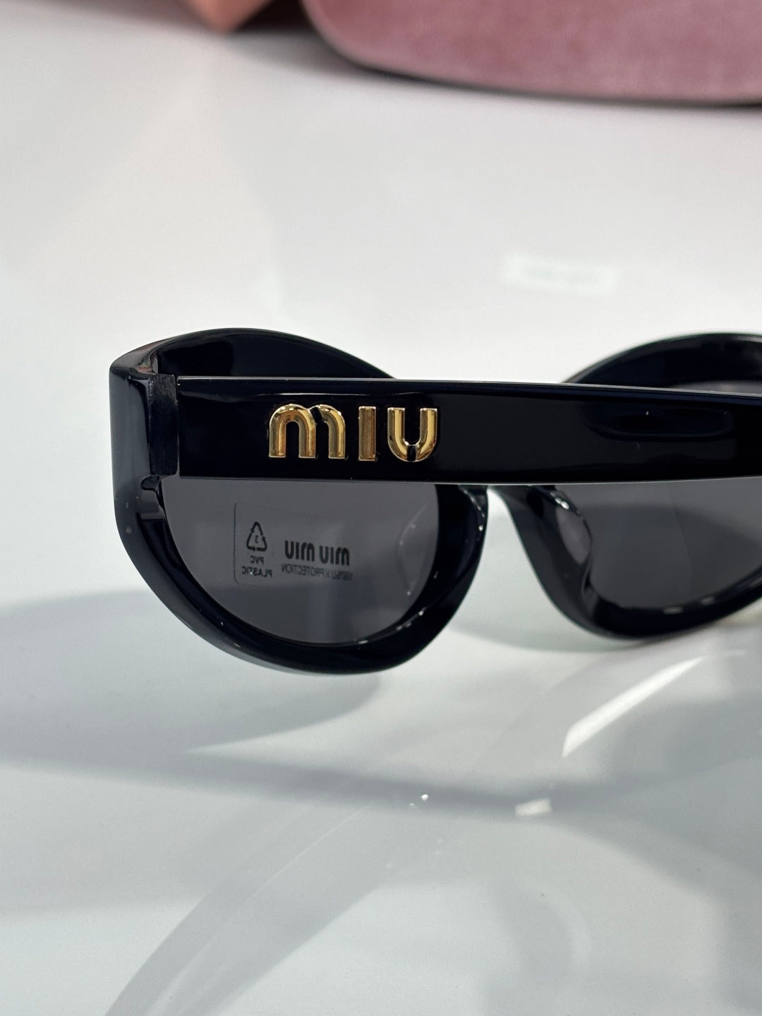 Black sunglasses with dark lenses and gold logo detail on the frame