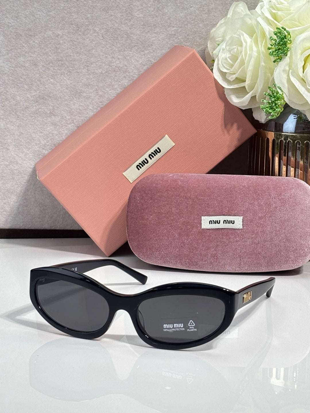 Black sunglasses with dark lenses; pink hard case and purple glasses pouch