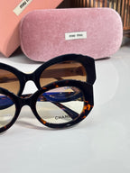 Round black sunglasses close-up with brown tinted lenses and logo on lens