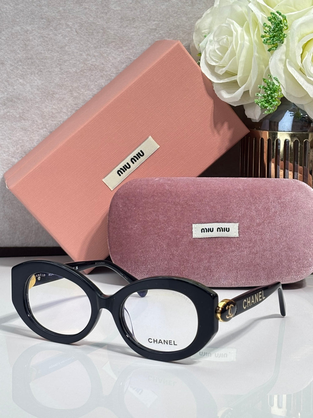 Designer glasses with black round frames and clear lenses, gold logo accents