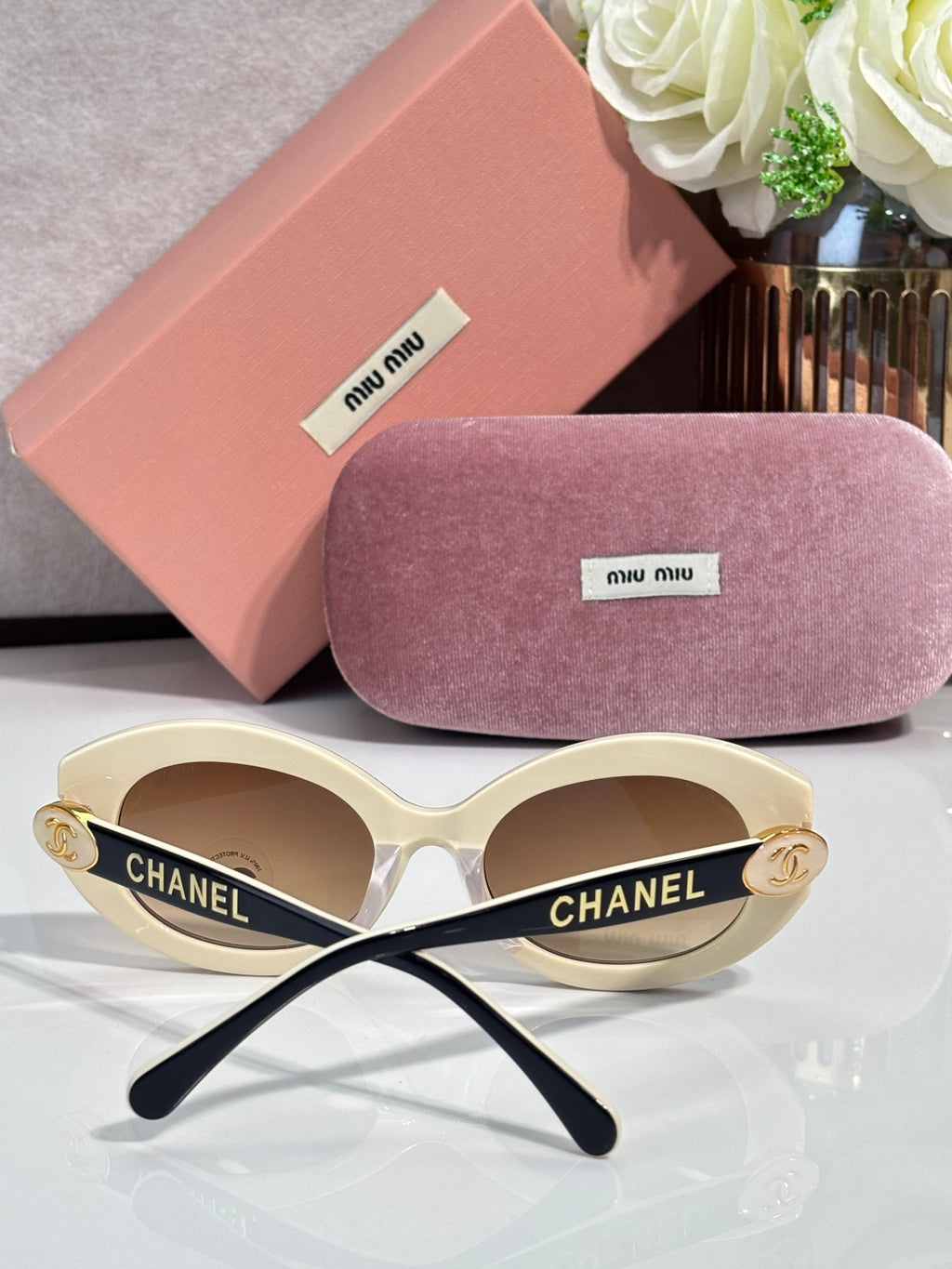 Designer cat-eye sunglasses with white frame, gold temples, and beige tinted lenses