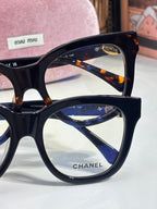Chanel sunglasses close-up: black frame with tortoise accents and blue-reflective lenses