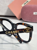 Chanel sunglasses close-up: black frame with tortoise temples and “CHANEL” detail