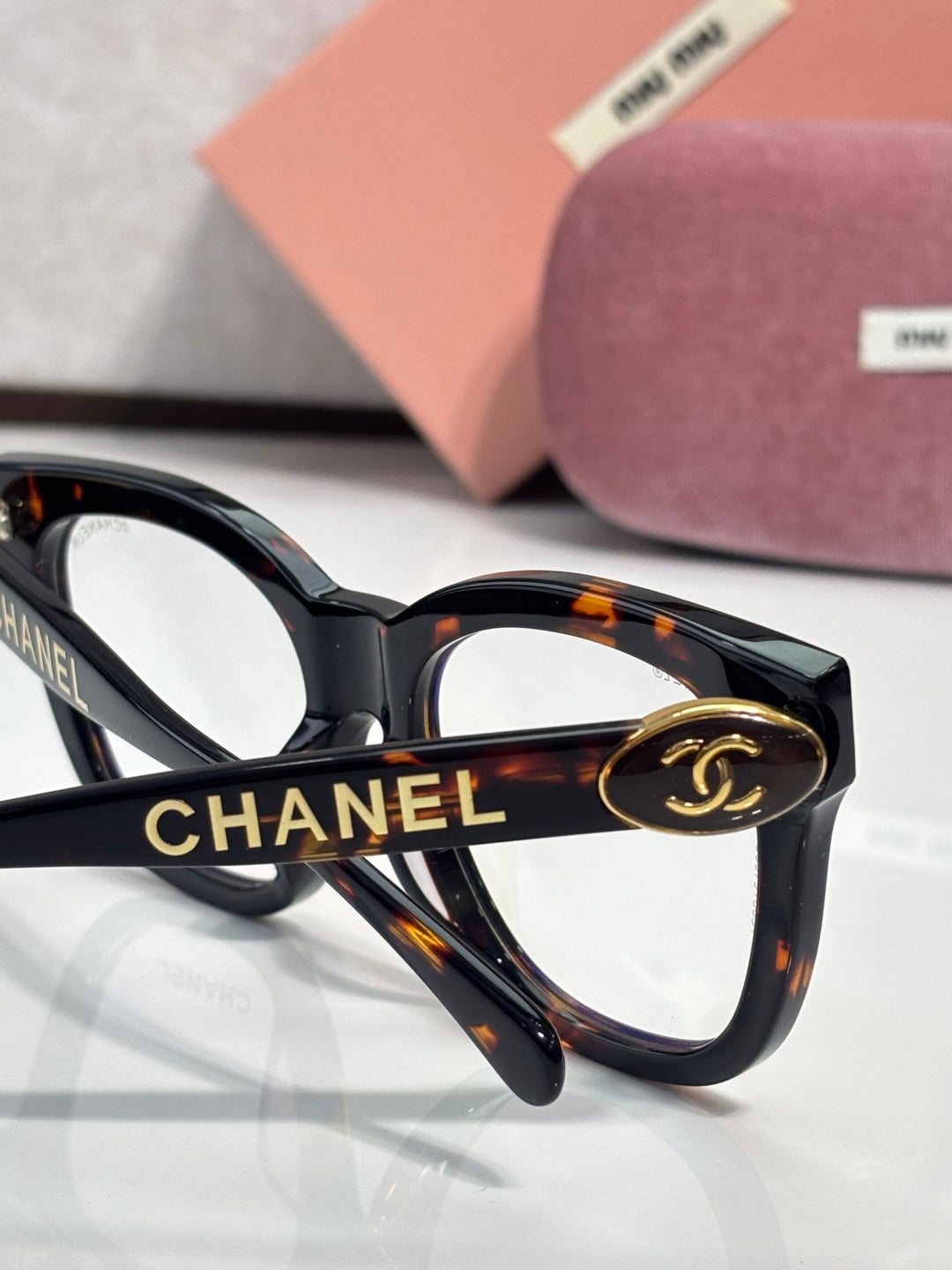 Chanel sunglasses close-up: black frame with tortoise temples and “CHANEL” detail