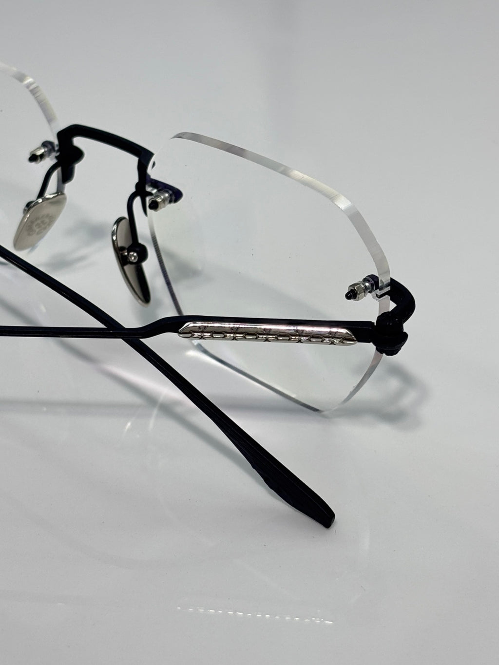 Black metal eyeglasses with clear lenses and engraved center bar