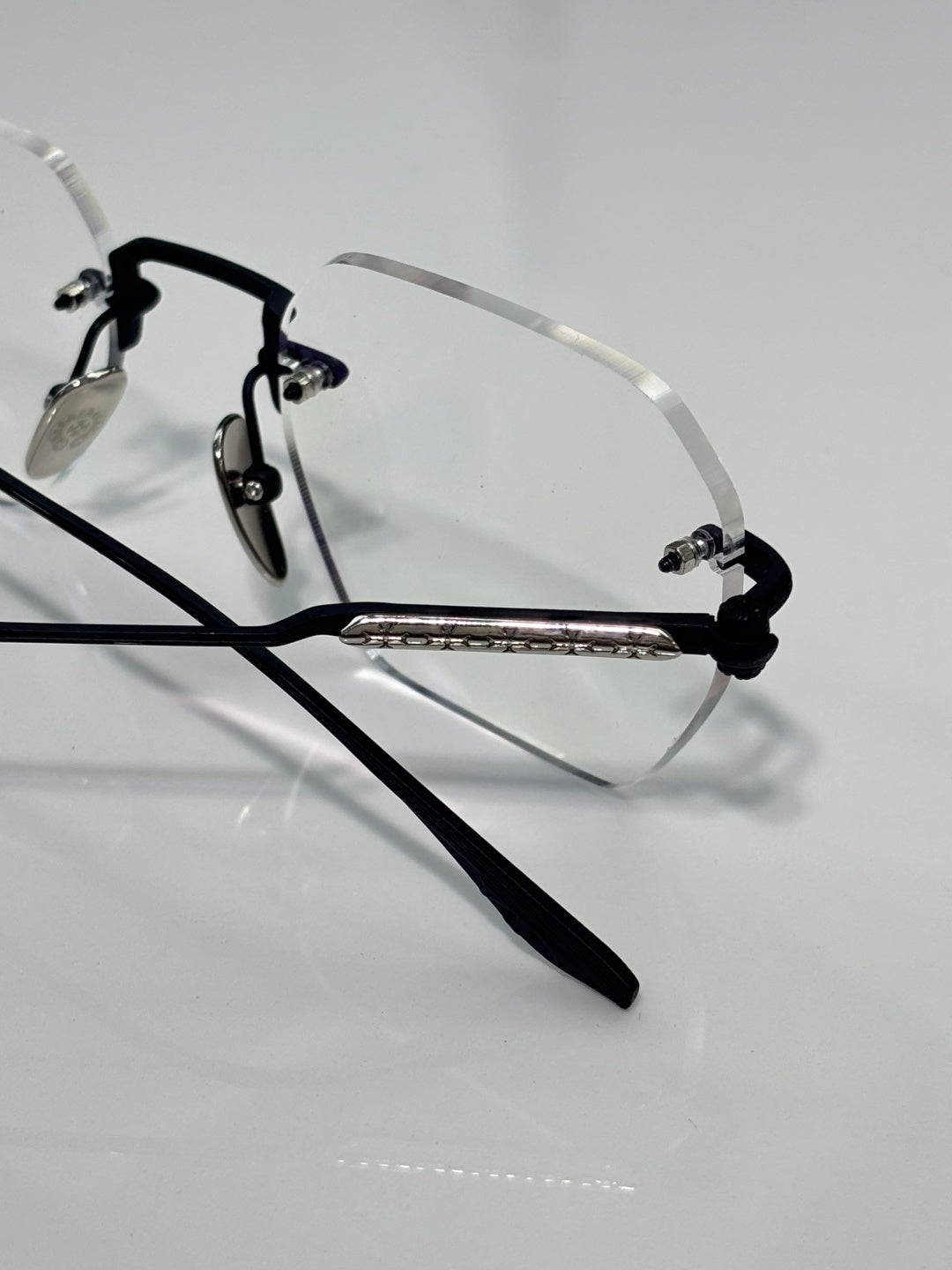 Black metal eyeglasses with clear lenses and engraved center bar