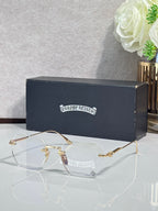 Gold metal eyeglasses with clear lenses and small round logo on temple