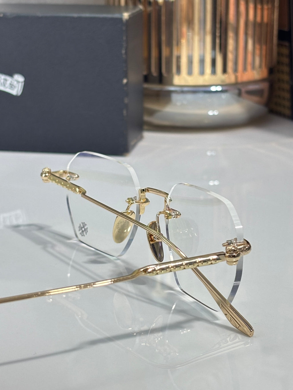 Close-up of gold metal eyeglasses with clear lenses and engraved temple