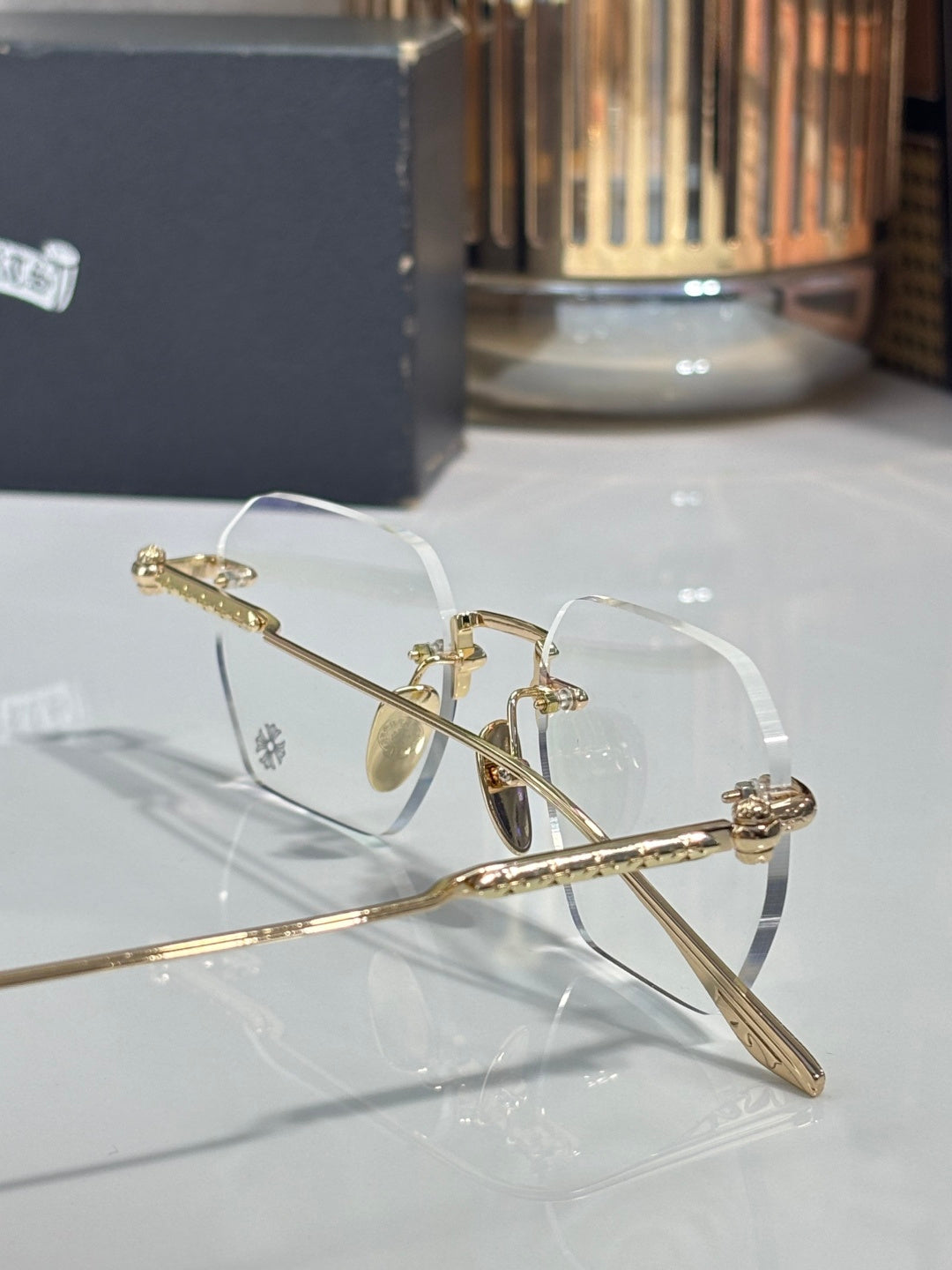 Close-up of gold metal eyeglasses with clear lenses and engraved temple
