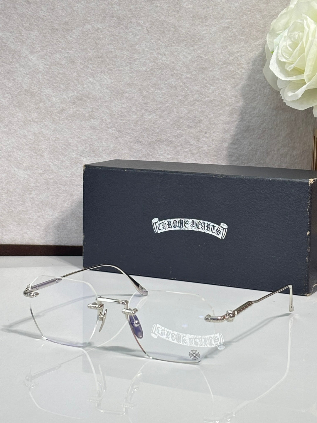 Metal eyeglasses with clear lenses, dark temple arms, and engraved side logo