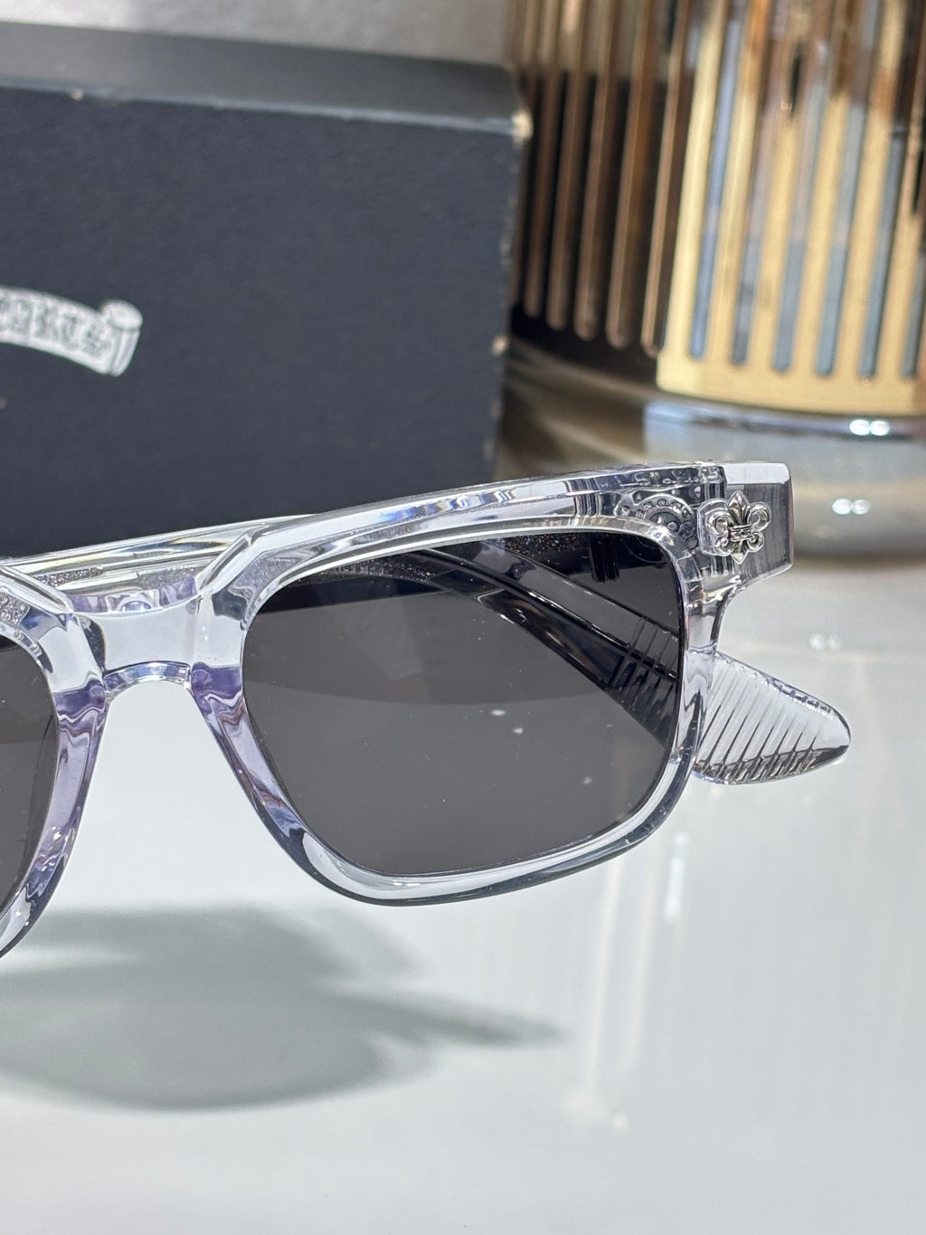 Chrome sunglasses front corner close-up with dark lens and ribbed temple tip