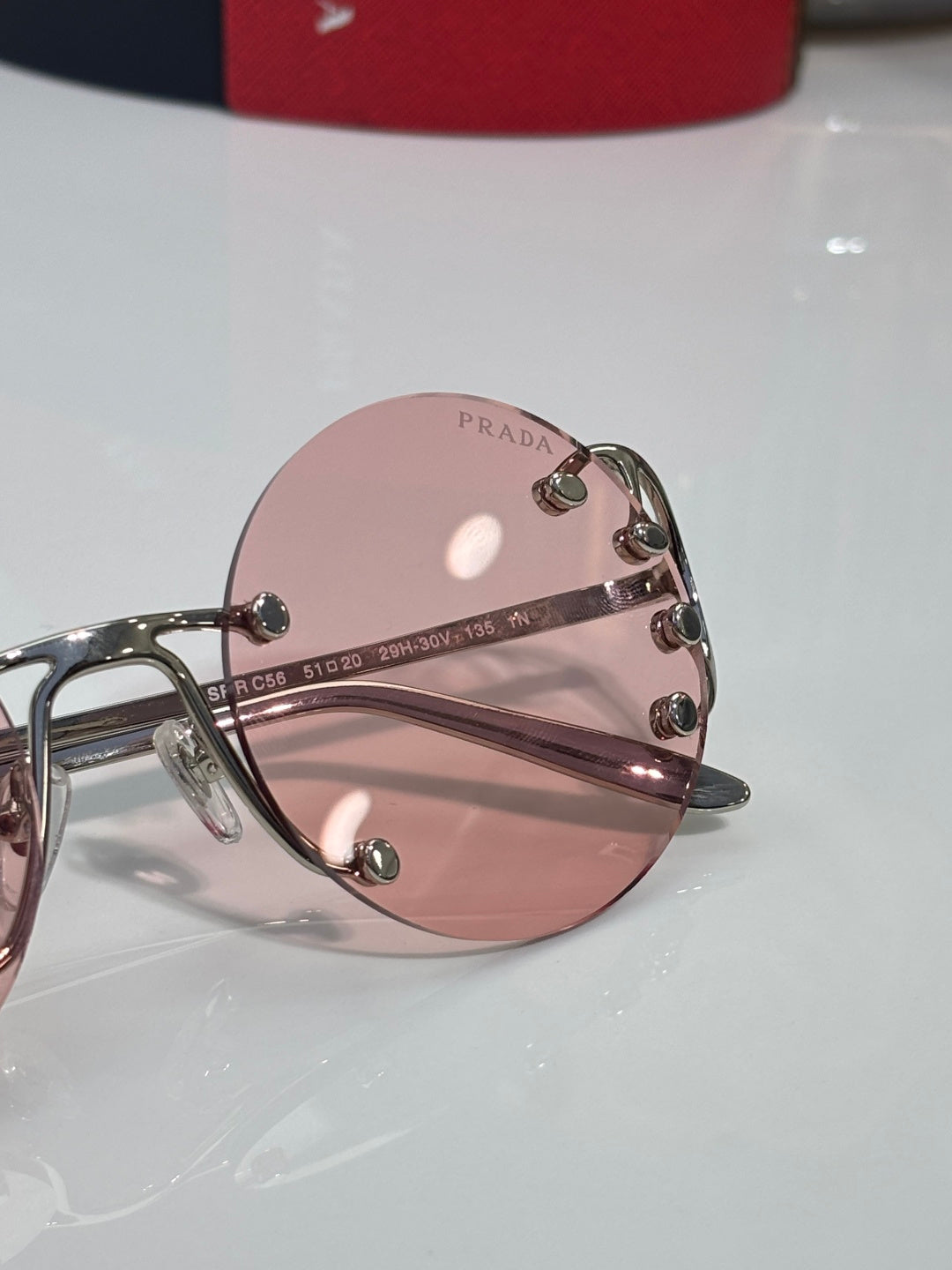 Prada round sunglasses close view of pink tinted lens and metal stud detail
