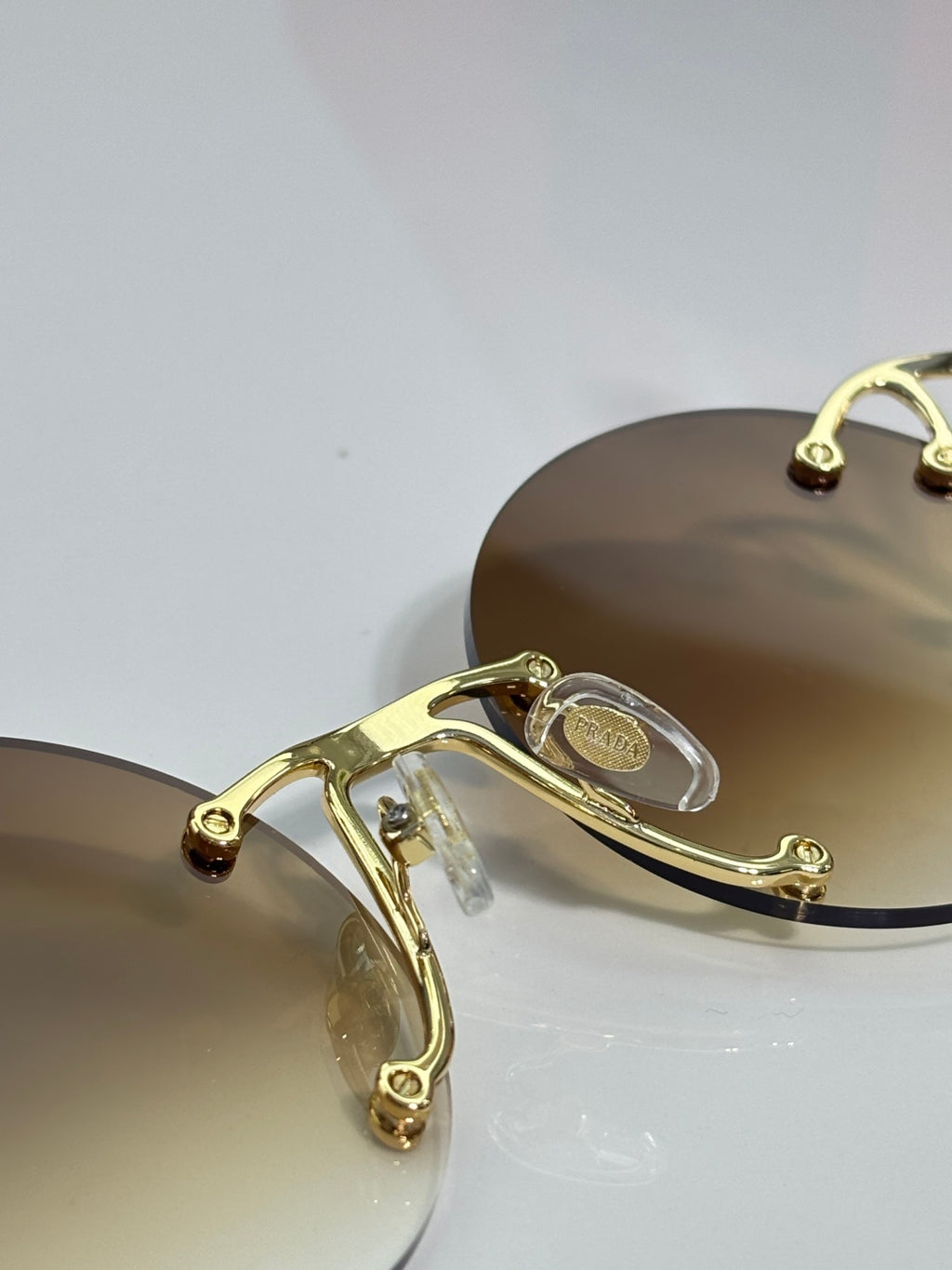 Prada round sunglasses close view of gold-tone metal bridge and hinges