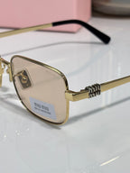 Close-up: gold-tone eyeglass frame with clear lens, black temple, and miu miu logo