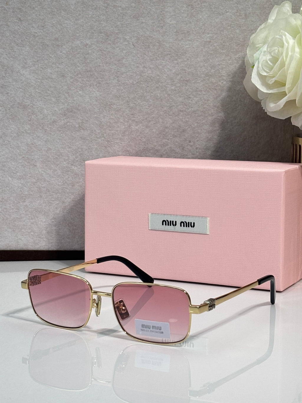Gold-tone square sunglasses with pink-tinted lenses and black temple tips