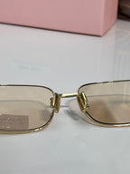 Close-up: gold-tone eyeglass frame with clear lenses and textured hinge detail
