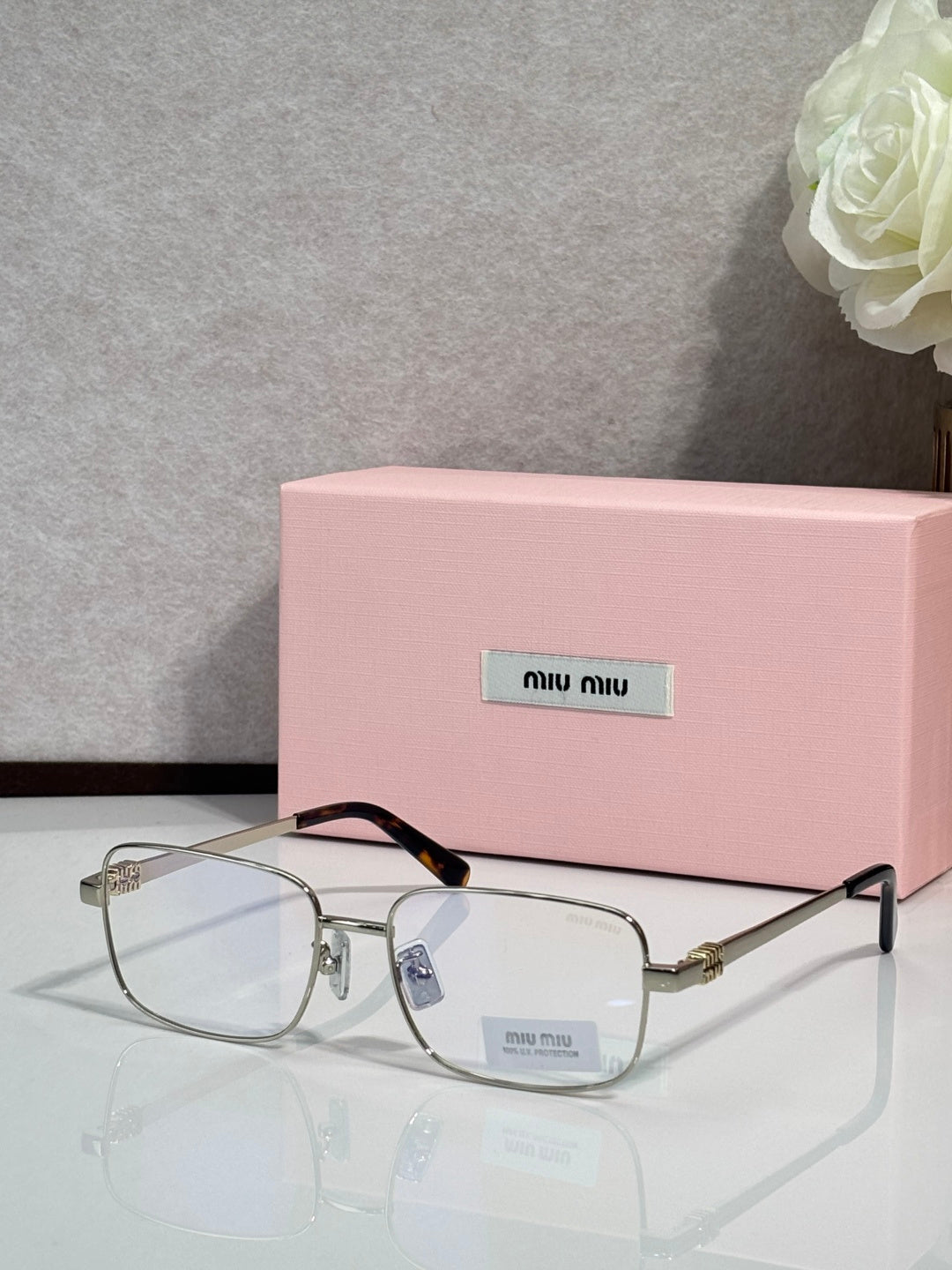 Gold-tone rectangular eyeglasses with clear lenses and black temple tips