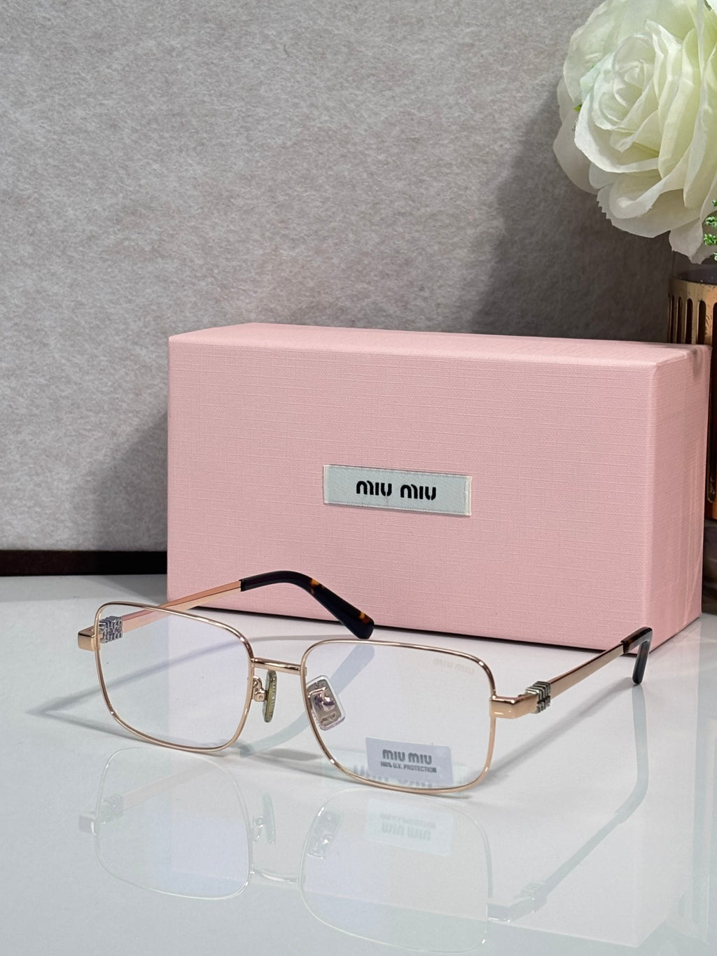 Gold-tone rectangular eyeglasses with clear lenses and black temple tips