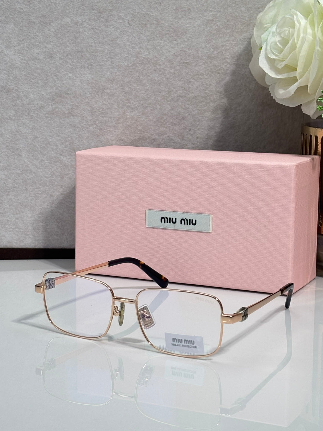 Gold-tone rectangular eyeglasses with clear lenses and black temple tips