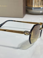 Close-up hexagon sunglasses: gold bridge with emblem, dark blue temple, tinted lenses